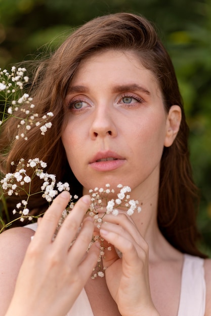 Retrato de mulher jovem posando com confiança ao ar livre com flores