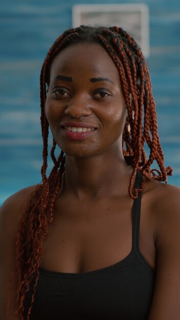 Retrato de mulher jovem sorrindo e olhando para a câmera durante o treino matinal de fitness sentado na bola de ioga na sala de estar