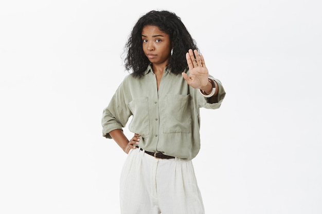 Foto grátis retrato de mulher morena adulta, mandona, confiante e descontente, com cabelo encaracolado, segurando a mão na cintura puxando a palma