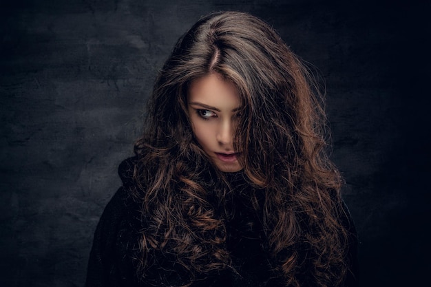 Retrato de mulher morena sensual com cabelo longo encaracolado, vestido de pulôver preto quente.