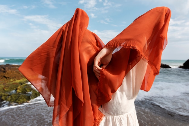 Retrato de mulher na praia cobrindo o rosto com véu