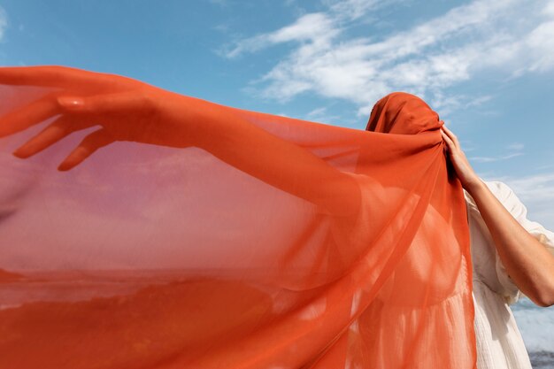 Retrato de mulher na praia cobrindo o rosto com véu