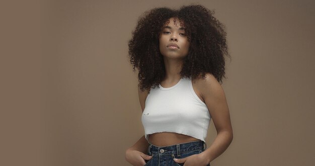 Retrato de mulher negra de raça mista com grande cabelo encaracolado afro em fundo bege