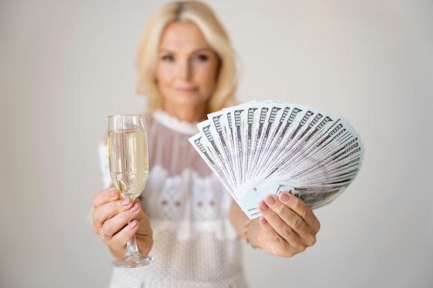 Retrato de mulher rica loira de meia-idade com taça de champanhe e notas