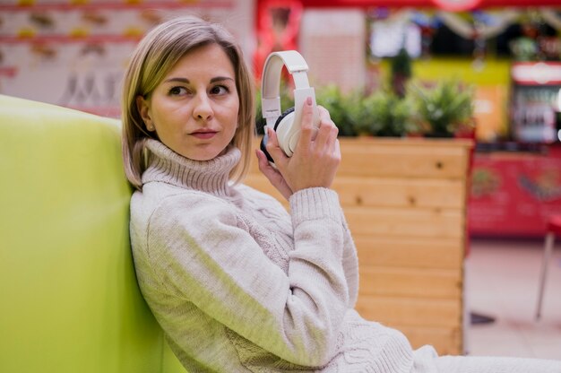 Retrato de mulher segurando fones de ouvido, sentado no sofá