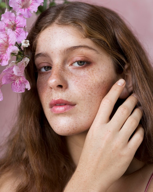 Retrato de mulher segurando uma flor rosa contra o rosto