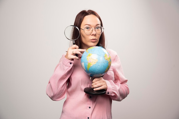 Foto grátis retrato de mulher segurando uma lupa e o globo terrestre. foto de alta qualidade