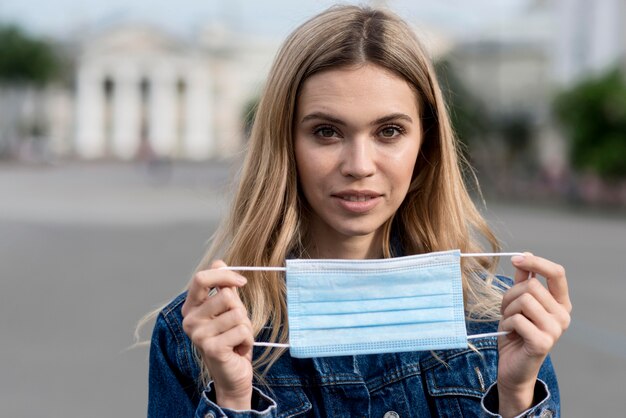 Retrato de mulher segurando uma máscara médica