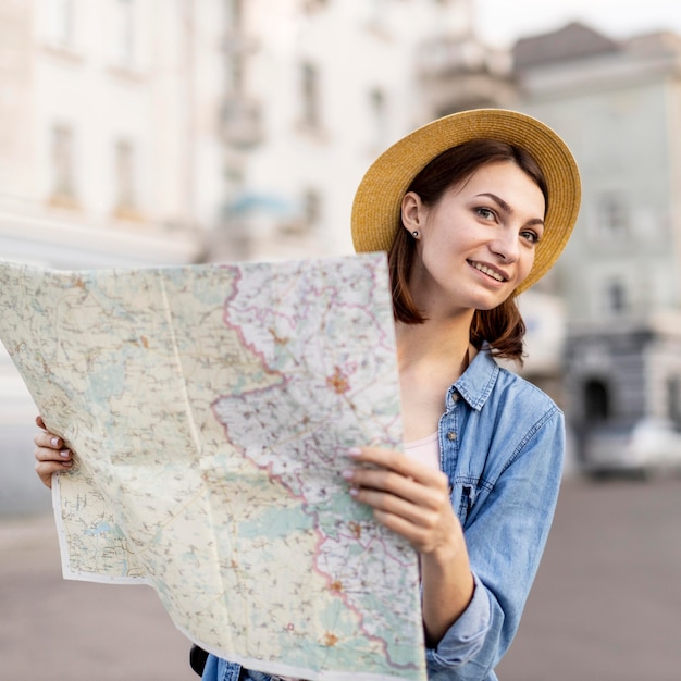 Retrato de mulher sorridente com chapéu segurando o mapa