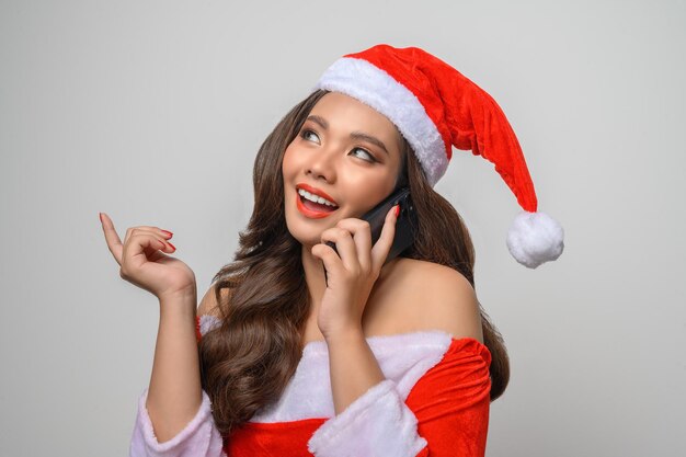 Retrato de mulher sorridente em papai noel vermelho mostrando smartphone