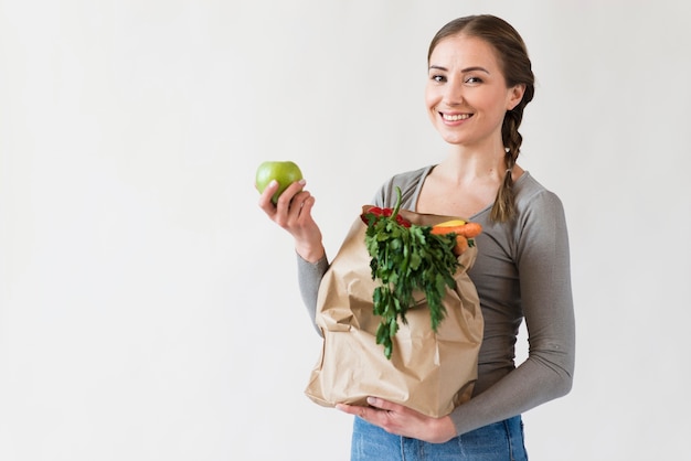 Retrato de mulher sorridente segurando o saco com frutas e legumes