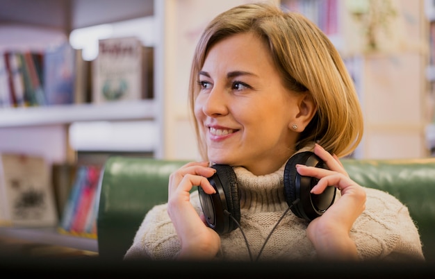 Retrato de mulher sorridente usando fones de ouvido, olhando para longe