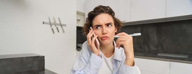 Retrato de mulher tendo uma conversa complicada segurando um smartphone franzindo a testa com frustração