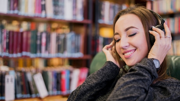 Retrato de mulher usando fones de ouvido, sorrindo com os olhos fechados