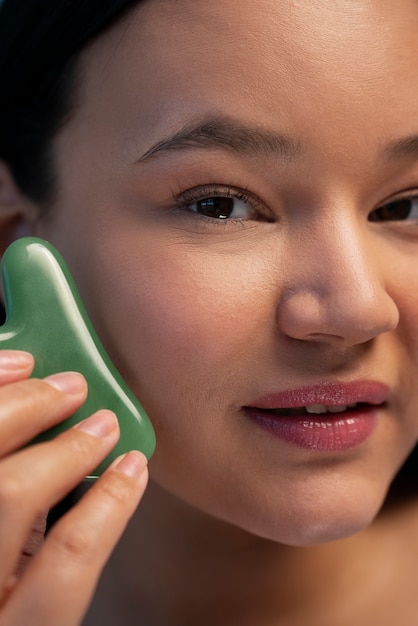 Retrato de mulher usando gua sha no rosto