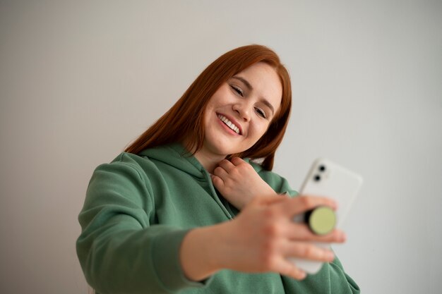 Retrato de mulher usando seu smartphone em casa no sofá, segurando na tomada pop