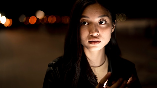 Retrato de mulher usando smartphone à noite nas luzes da cidade