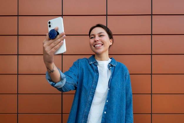 Foto grátis retrato de mulher usando smartphone com pop socket ao ar livre