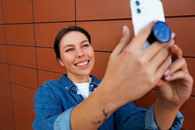 Foto grátis retrato de mulher usando smartphone com pop socket ao ar livre