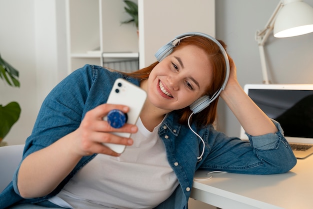 Foto grátis retrato de mulher usando smartphone em casa com pop socket