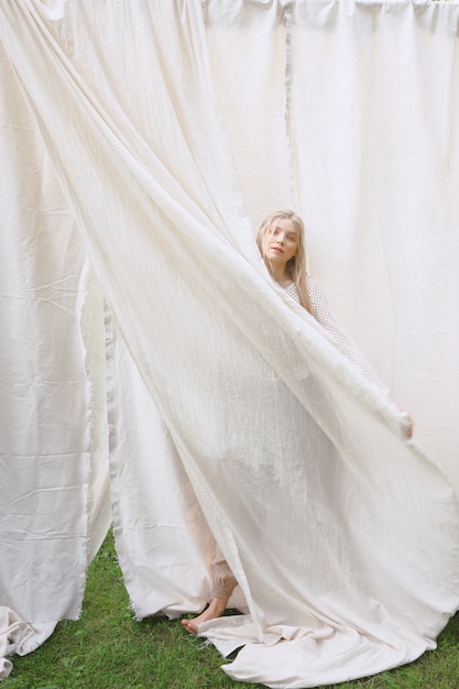 Foto grátis retrato de mulheres bonitas no jardim, estando e guardando o pano no vestido branco durante o dia.