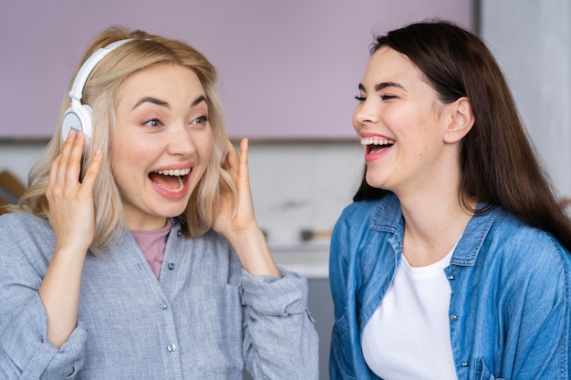 Retrato de mulheres felizes rindo e ouvindo música em fones de ouvido