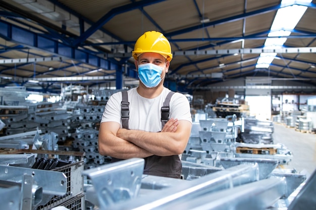 Retrato de operário de fábrica de uniforme e capacete usando máscara facial em uma planta de produção industrial