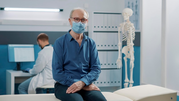 Retrato de paciente sênior participando de exame de recuperação em gabinete com clínico geral durante a pandemia de covid 19. consulta de medicina alternativa com especialista em consultório de saúde.