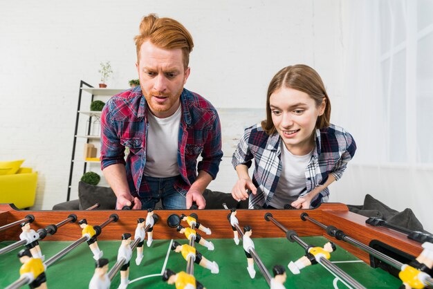 Retrato, de, par jovem, desfrutando, jogando futebol, jogo, casa