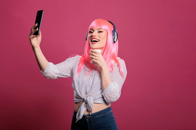 Retrato de pessoa legal ouvindo música e tirando fotos, usando o aplicativo de celular para se divertir com fotos. Fazendo fotografia e fone de ouvido sem fio, sentindo-se feliz e positivo.