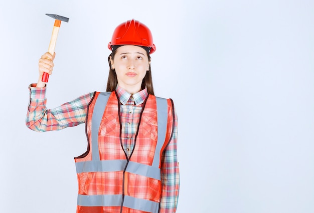 Foto grátis retrato de reparador feminino de uniforme segurando o martelo sobre a parede branca.