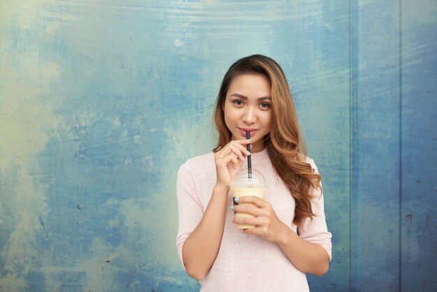 Foto grátis retrato de senhora encantadora, desfrutando de milkshake, olhando para a câmera