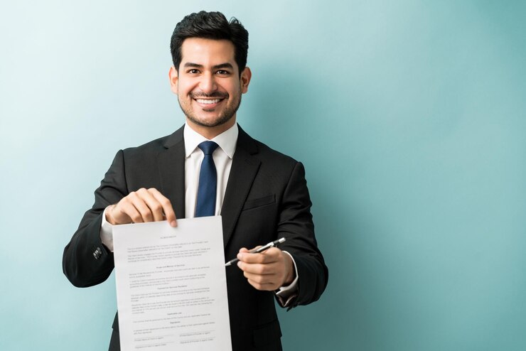 Foto grátis retrato de sorridente jovem profissional masculino confiante com contrato contra fundo colorido