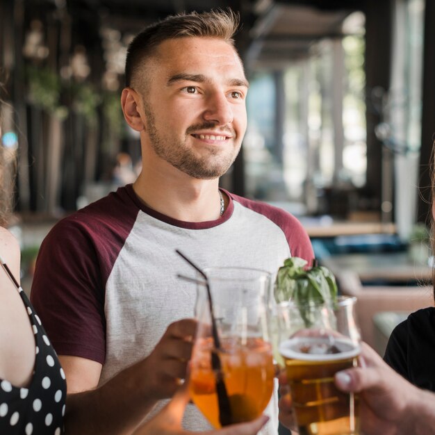 Retrato, de, sorrindo, homem jovem, brindar, bebidas, com, seu, amigos