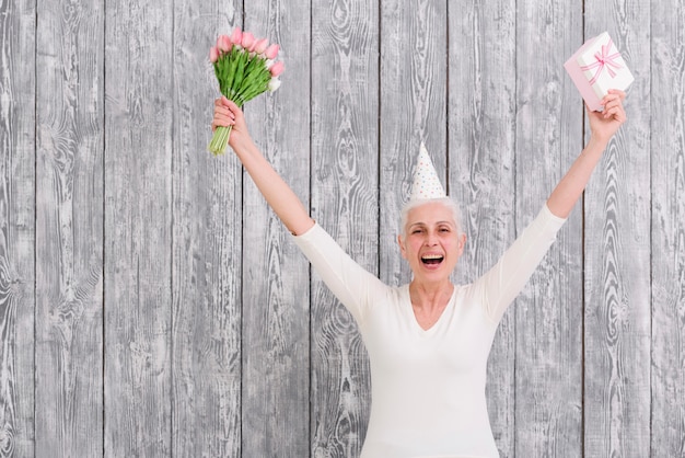 Retrato, de, sorrir, aniversário, mulher segura, buquê flor, com, caixa presente, frente, fundo madeira