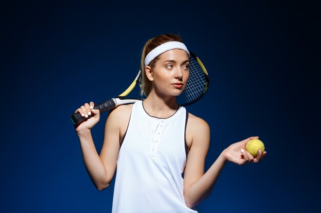 retrato de tenista com raquete no ombro e bola na mão posando