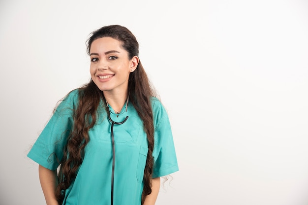 Retrato de trabalhador de saúde feminino posando na parede branca.