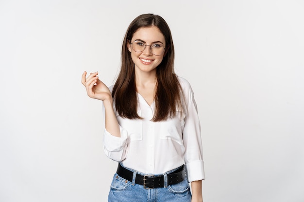 Retrato de trabalhadora de escritório feminina, empresária olhando para a câmera e sorrindo, de pé sobre fundo branco