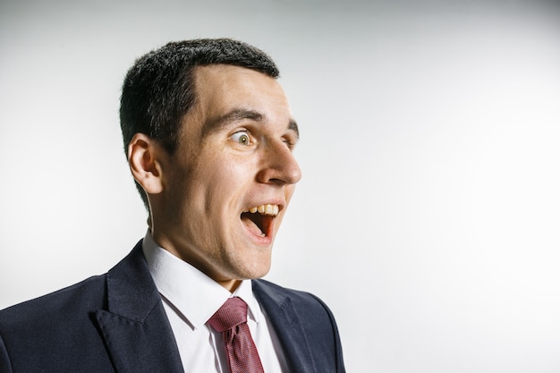 Retrato de três quartos de um empresário com cara de surpresa e sorridente. profissional confiante com olhar penetrante em primeiro plano da câmera.