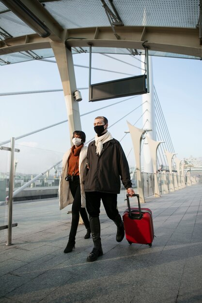 Foto grátis retrato de turistas com máscaras médicas e bagagem