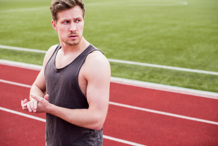 Foto grátis retrato de um atleta do sexo masculino em pé na pista de corrida, olhando para longe