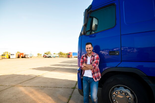 Retrato de um caminhoneiro sorridente ao lado de seu caminhão, pronto para dirigir