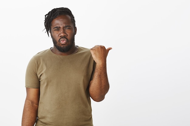 Retrato de um cara chocado com uma camiseta marrom posando contra a parede branca