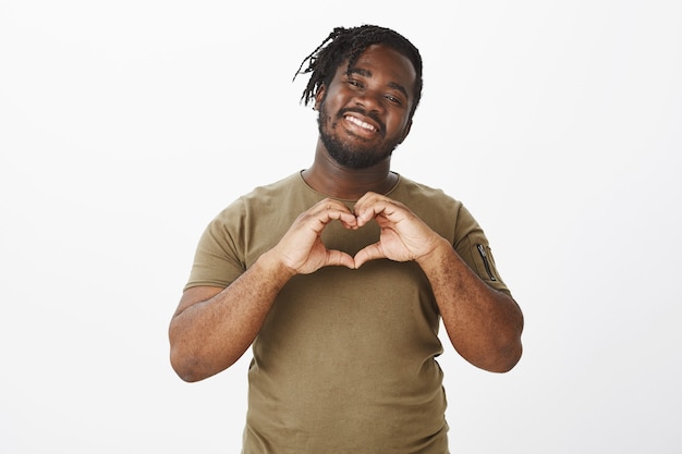 Retrato de um cara feliz em uma camiseta marrom posando contra a parede branca