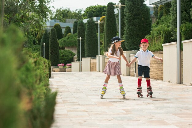 Retrato de um casal adolescente encantador patinando juntos de patins no parque. Menino adolescente e menina caucasianos.