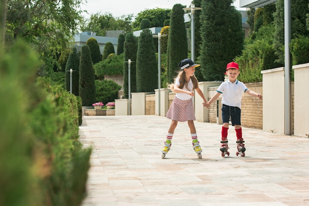 Retrato de um casal adolescente encantador patinando juntos de patins no parque. Menino adolescente e menina caucasianos.