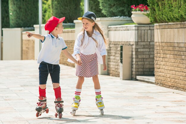 Retrato de um casal adolescente encantador patinando juntos de patins no parque.