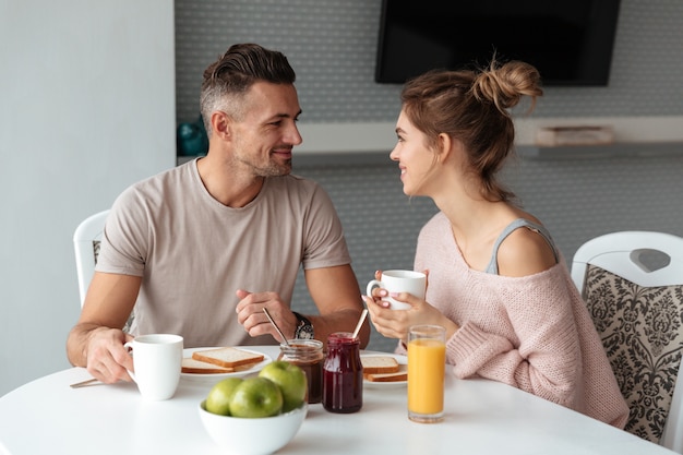 Retrato de um casal apaixonado sorridente tomando café da manhã