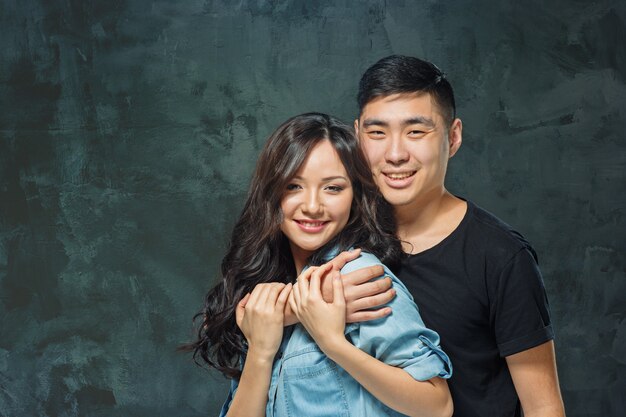 Retrato de um casal coreano sorridente em um fundo cinza de estúdio
