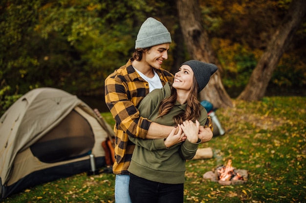 Retrato de um casal feliz e apaixonado de turista em roupas casuais na floresta perto da tenda